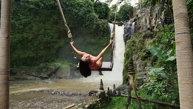 Beautiful girl having fun at the waterfalls in Bali. Concept about wanderlust traveling and wilderness culture