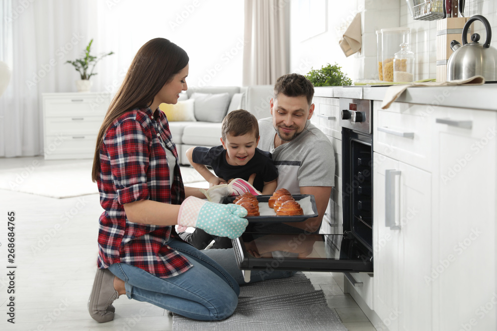 Canvas Prints Woman and her family taking out tray with baked buns from oven in kitchen