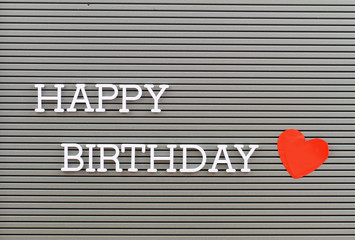 Happy birthday written with plastic letters on metal board and red heart