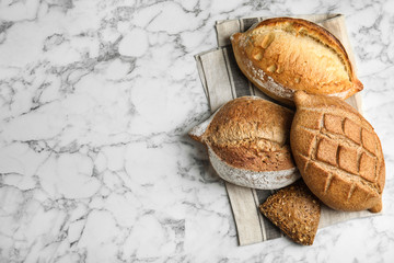 Different kinds of fresh bread on marble table, top view with space for text