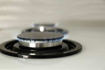 Gas burner with blue flame on modern stove, closeup. Space for text