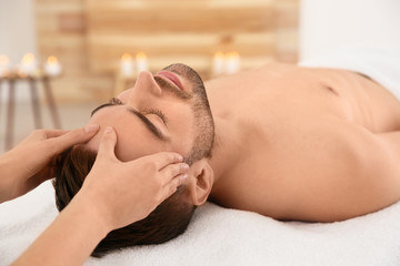 Obraz na płótnie Canvas Handsome man receiving face massage in spa salon