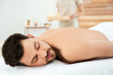 Fototapeta na wymiar Handsome man relaxing on massage table in spa salon