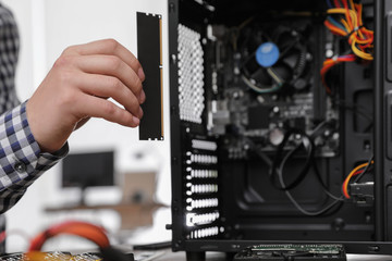 Fototapeta premium Male technician putting RAM chip into system unit, closeup. Computer repair