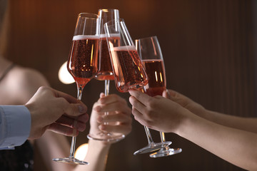 Friends clinking glasses with champagne on blurred background, closeup