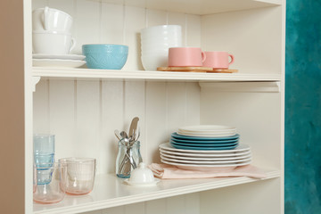 Obraz na płótnie Canvas White shelving unit with set of dishware near wall