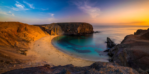 Romantic sunset over the beautiful, natural and sandy beach of Papagayo on Lanzarote - obrazy, fototapety, plakaty