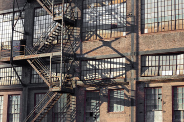 Fototapeta na wymiar Abandoned brick warehouse with broken windows and fire escape, horizontal aspect