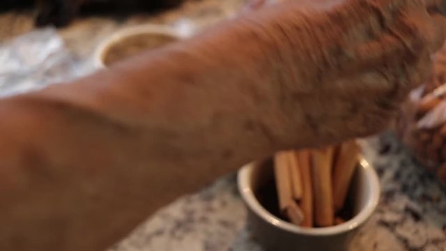 Top view Cloves, pepper grains and cinnamon on the table. Tipical ingredients of original Mole from Puebla, Woman putting some cinnamon in the bowl. Mexico. North America. Cooking Traditional recipe