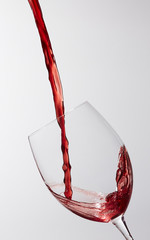 A stream of red wine being poured into a wineglass
