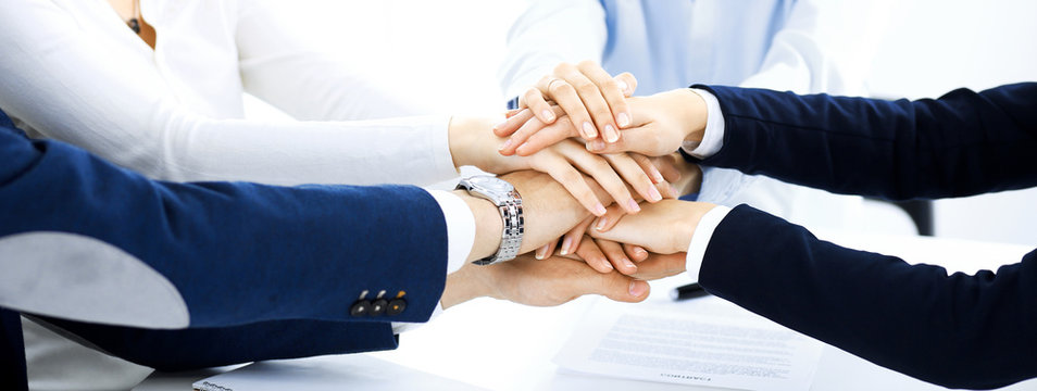 Business team showing unity with their hands together. Group of people joining hands and representing concept of friendship, teamwork and partnership