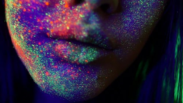  Beautiful young woman dancing and making party with fluorescent painting on her face. Neon facial portraits
