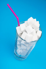 Concept of excessive sugar consumption is harmful to health. Sugar cubes on the glass.