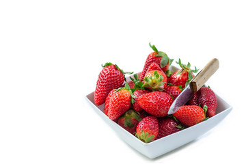 Fresh organic red strawberries in a ceramic bowl on white background