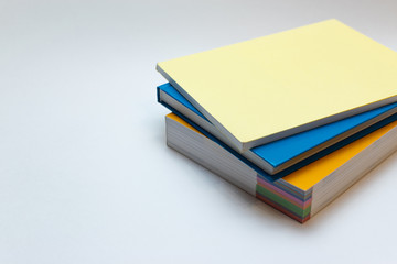 Multicolored books stacked on a white background. Dictionary, textbook and notebook on a white table.  Literature for learning in yellow and blue covers