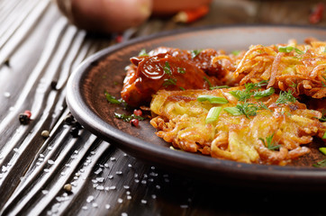 Closeup view at Homemade tasty potato pancakes in clay dish with sun-dried tomatoes