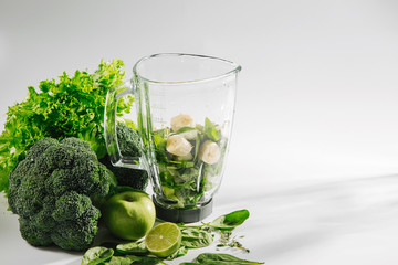 Ingredients for green smoothies in a blender. Healthy food concept with spinach and green vegetables. Vegetarian food.