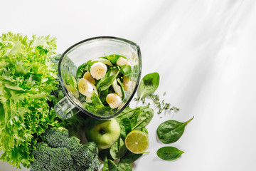 Ingredients for green smoothies in a blender. Healthy food concept with spinach and green vegetables. Vegetarian food.