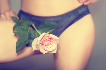 Sexy girl in blue panties holds a rose between her legs, causing temptation and temptation.
