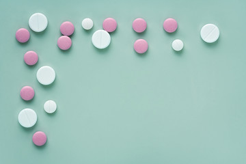 corner border of white and pink round pills on a light green background with space for text