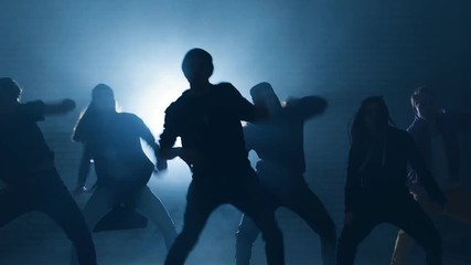Teens taking part in dancing battle outside. Group of street dancers performing different moves on dark street