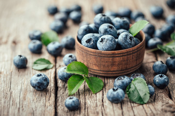 Freshly picked blueberries in wooden bowl on wooden background. Healthy eating and nutrition.