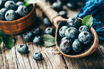 Blueberries in wooden spoon on old wood table. Healthy eating and nutrition concept.