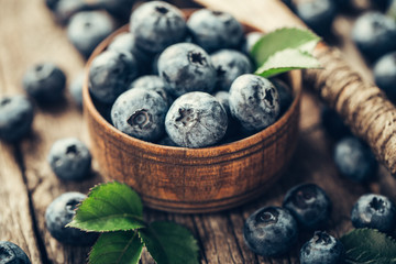 Blueberries in wooden spoon on old wood table. Healthy eating and nutrition concept.