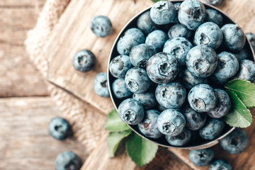 Freshly picked blueberries in wooden bowl on wooden background. Healthy eating and nutrition.