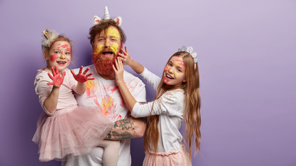 Emotive single father spends free time with daughters, paint faces, use watercolors, two kids have...