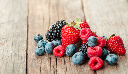 Fresh Summer Berries mix with Strawberry, Raspberry, Red currant, Blueberry and Blackberry on wood background.