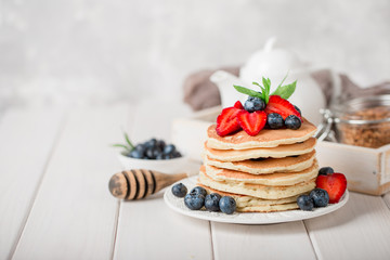 Classic american pancakes with fresh berry on white wood background. Summer homemade breakfast. - obrazy, fototapety, plakaty
