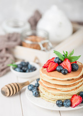 Classic american pancakes with fresh berry on white wood background. Summer homemade breakfast.
