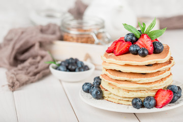 Classic american pancakes with fresh berry on white wood background. Summer homemade breakfast.