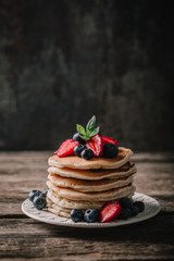 American pancakes with fresh berry on wood background. Summer homemade breakfast.