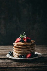 American pancakes with fresh berry on wood background. Summer homemade breakfast.