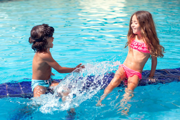 Little boy and girl play in the swimming pool. Children and summer concept