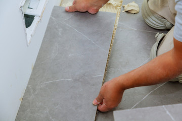 Troweling mortar a concrete floor in preparation for laying floor tile.