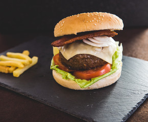 Delicious burgers with beef patty, bacon, cheese and cabbage with fries potatoes
