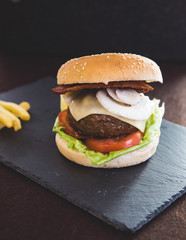 Delicious burgers with beef patty, bacon, cheese and cabbage with fries potatoes