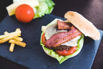 Delicious burgers with beef patty, bacon, cheese and cabbage with fries potatoes