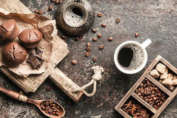 Coffee beans with coffee and muffins on dark textured background.