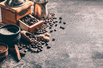 Coffee with coffee grinder and coffee beans on dark textured background.