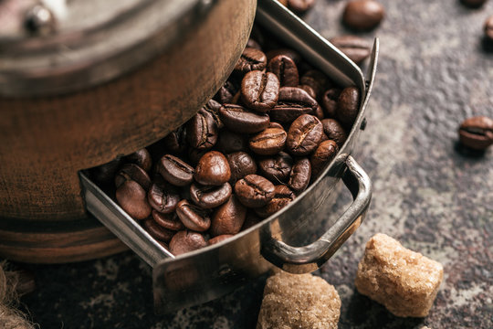 Coffee with coffee grinder and coffee beans on dark textured background.
