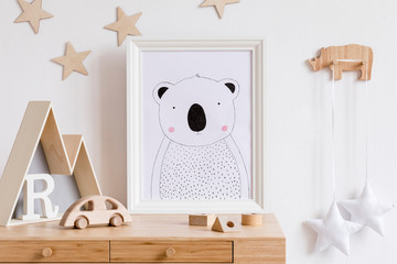 Stylish scandi childroom with white mock up photo frame, wooden accessories, toys, mountain box and...