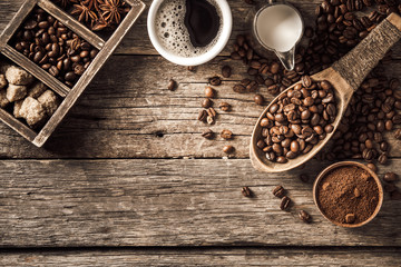 Coffee cup with coffee beans on wood background.