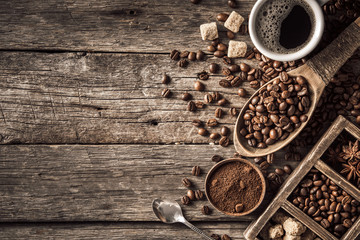 Coffee cup with coffee beans on wood background.