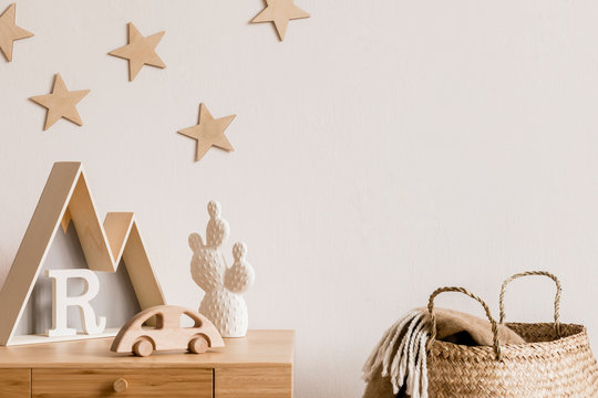 Stylish and cozy childroom with wooden accessories, toys, mountain box, car, basket and stars pattern on the background wall. Bright and sunny interior. Template, Real photo.