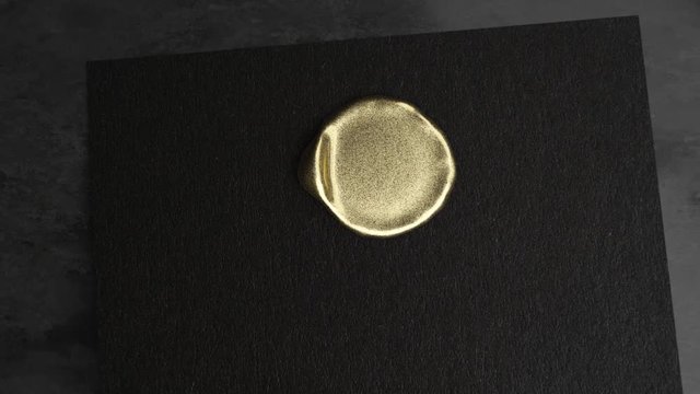 Golden wax drop to black paper and golden stamp make a seal