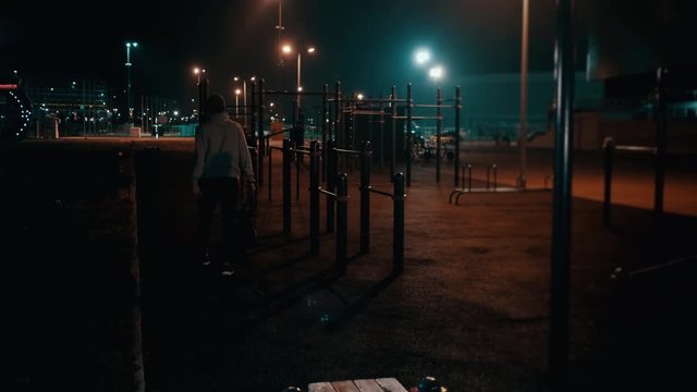 Young man is going out from sports ground in park at night